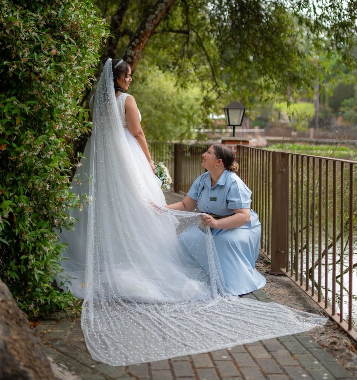 Wedding planner a ajustar o véu de pérolas da noiva junto a um lago